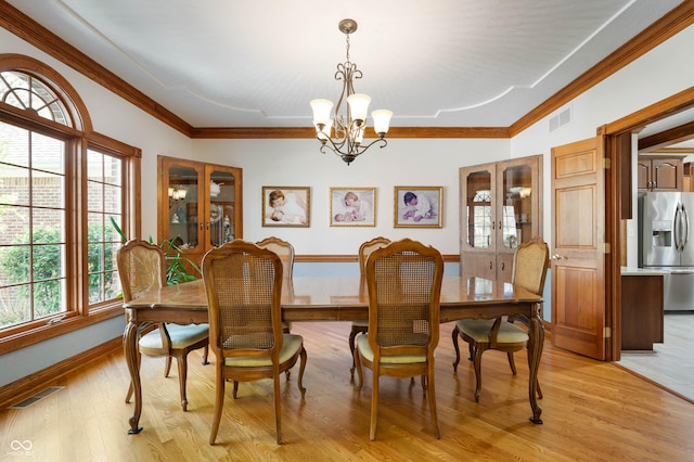 dining space with crown molding, a chandelier, french doors, light wood-style flooring, and visible vents