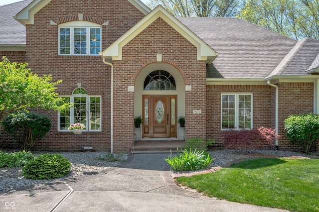 property entrance with a shingled roof and brick siding