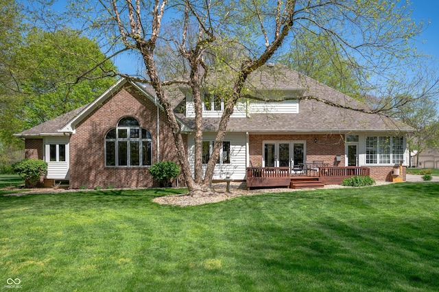 rear view of property with a lawn, a wooden deck, a shingled roof, and brick siding