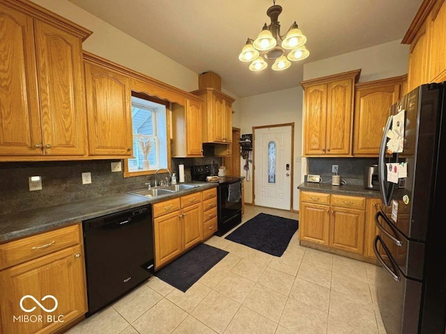 kitchen with dark countertops, a sink, a chandelier, backsplash, and black appliances