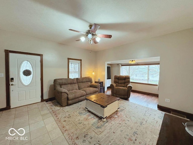 living area with baseboards, ceiling fan, and a wealth of natural light