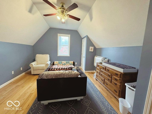 bedroom featuring baseboards, a ceiling fan, wood finished floors, and vaulted ceiling