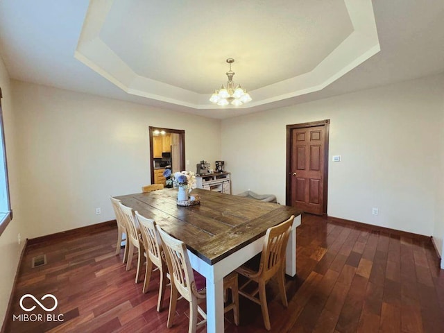 dining room featuring visible vents, a raised ceiling, baseboards, and a notable chandelier