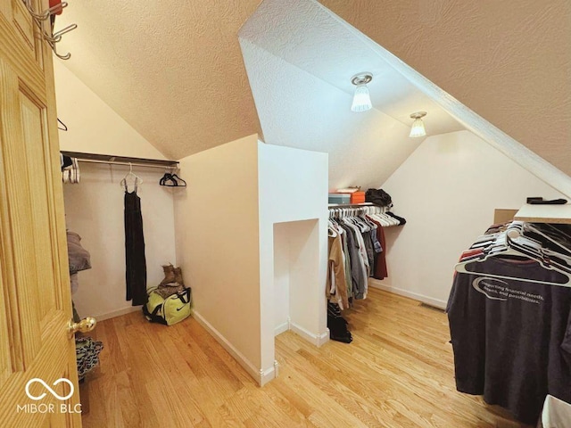 spacious closet with light wood-type flooring and vaulted ceiling
