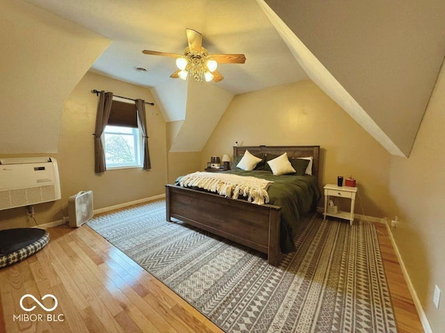 bedroom featuring baseboards, wood finished floors, and lofted ceiling