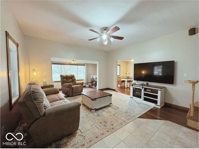 living area with ceiling fan, baseboards, and tile patterned flooring