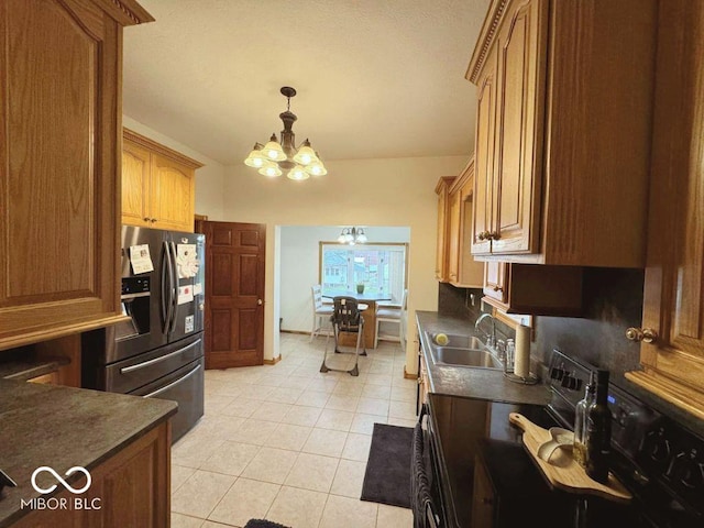 kitchen with electric range, stainless steel refrigerator with ice dispenser, dark countertops, a sink, and a notable chandelier