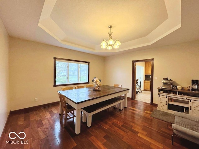 dining space with a tray ceiling, an inviting chandelier, baseboards, and dark wood-type flooring