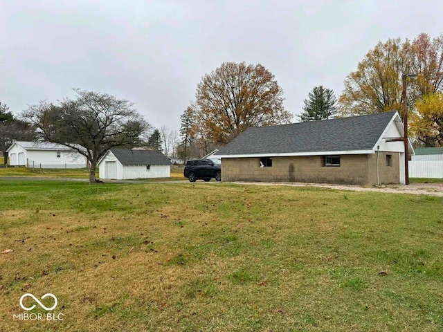 view of home's exterior with roof with shingles, a lawn, an outbuilding, a garage, and concrete block siding