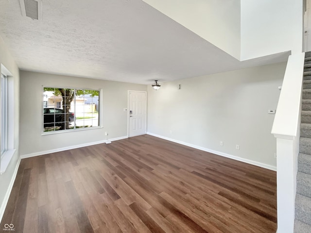 6628 Dunsdin Dr, Plainfield, IN 46168 - unfurnished living room with a textured ceiling, visible vents, stairway, baseboards, and dark wood-style floors