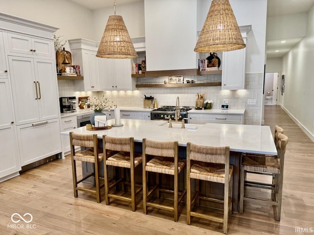 kitchen with a sink, tasteful backsplash, open shelves, and light wood-style flooring