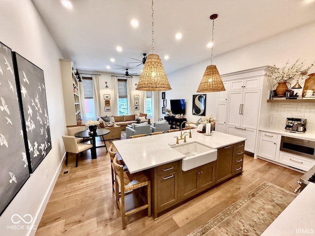 kitchen with a sink, light wood-style flooring, recessed lighting, open floor plan, and decorative backsplash