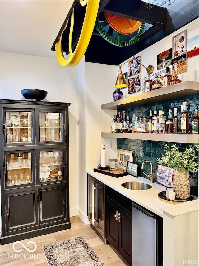 bar with a sink, indoor wet bar, fridge, and light wood-type flooring