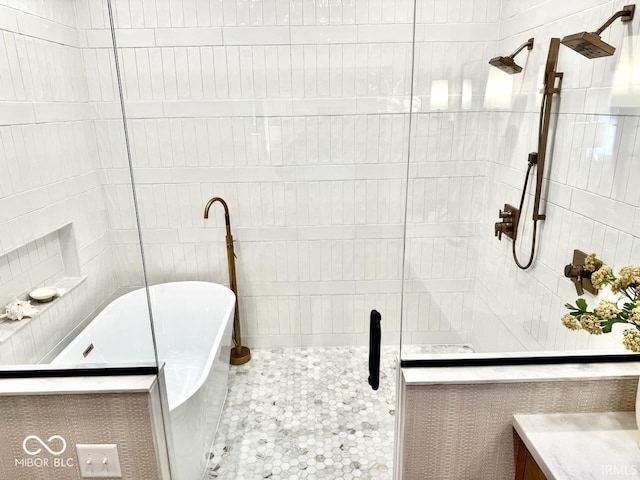 full bathroom featuring a freestanding tub, a shower stall, and tile walls