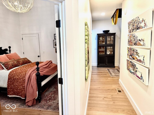 bedroom featuring baseboards, visible vents, an inviting chandelier, and light wood-type flooring