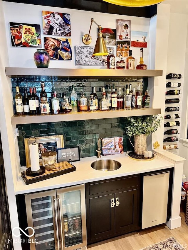 bar with light wood-style floors, a sink, wet bar, and wine cooler