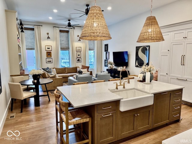 kitchen featuring visible vents, open floor plan, light wood-style floors, and a ceiling fan