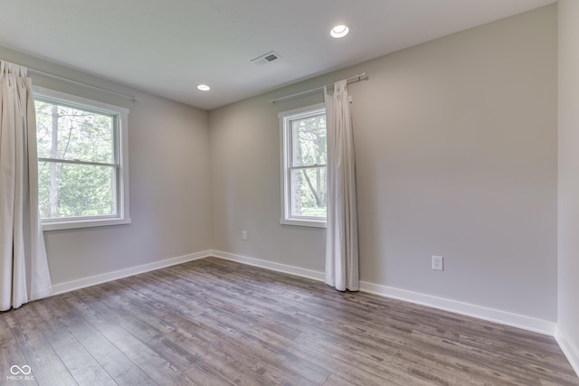 spare room with healthy amount of natural light, wood finished floors, baseboards, and recessed lighting