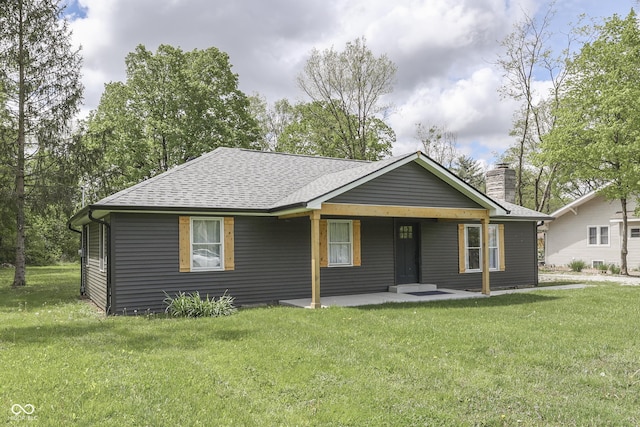 bungalow-style home with a shingled roof, a front yard, a chimney, and a patio