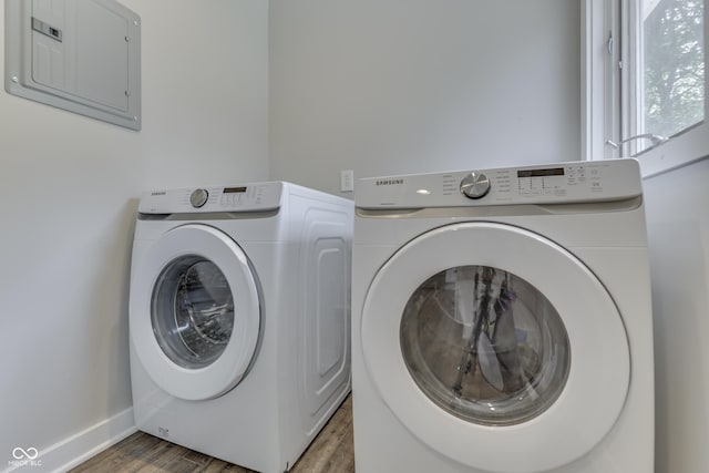 laundry room featuring washer and dryer, electric panel, wood finished floors, and baseboards