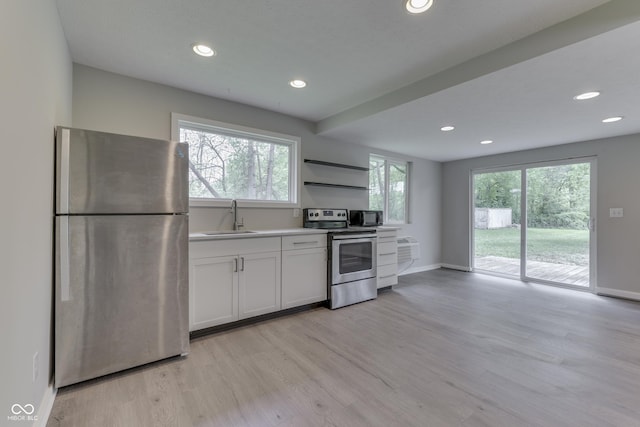 kitchen featuring stainless steel appliances, a sink, light wood finished floors, plenty of natural light, and recessed lighting