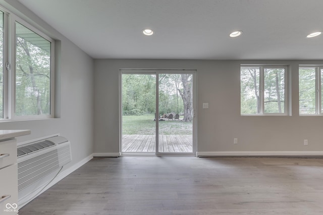 unfurnished living room featuring recessed lighting, baseboards, wood finished floors, and a wall mounted AC