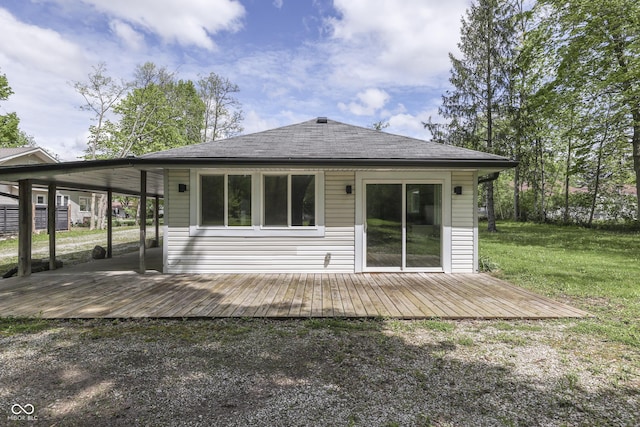 back of property featuring a deck, a shingled roof, and a yard
