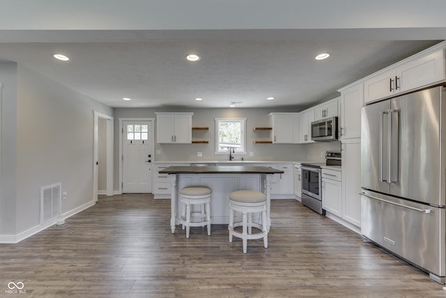 kitchen featuring appliances with stainless steel finishes, open shelves, a kitchen breakfast bar, recessed lighting, and white cabinetry