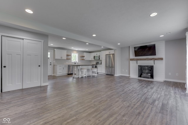 unfurnished living room with wood finished floors, baseboards, recessed lighting, and a fireplace