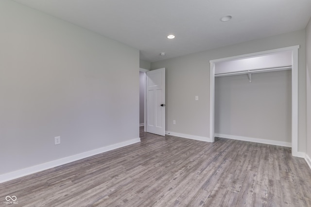 unfurnished bedroom with wood finished floors, baseboards, a closet, and recessed lighting