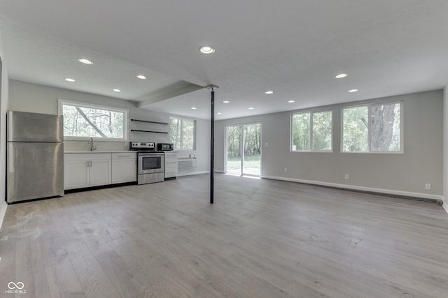 unfurnished living room with a sink, light wood-style floors, recessed lighting, and baseboards
