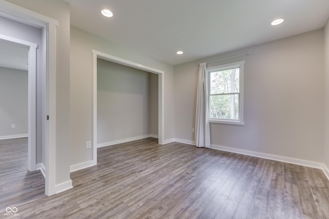 unfurnished bedroom featuring wood finished floors, baseboards, recessed lighting, and a closet