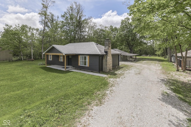 view of front facade featuring driveway, a chimney, a front lawn, a porch, and a carport