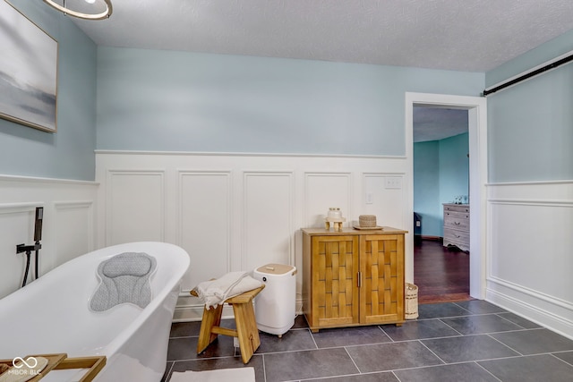 interior space featuring a decorative wall, dark tile patterned flooring, and a wainscoted wall