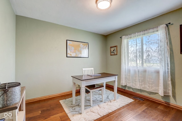home office featuring baseboards, hardwood / wood-style floors, and visible vents