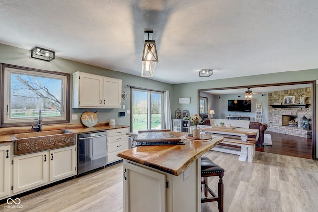 kitchen featuring white cabinets, light wood-type flooring, a sink, and dishwasher