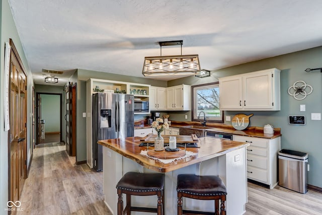 kitchen with white cabinetry, appliances with stainless steel finishes, a sink, and light wood-style floors