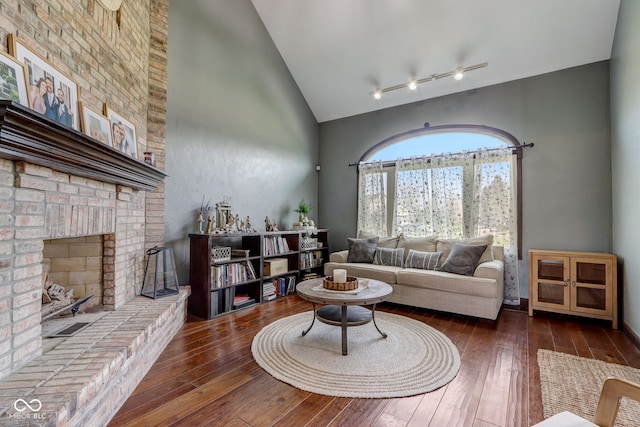living room with a brick fireplace, high vaulted ceiling, and hardwood / wood-style flooring