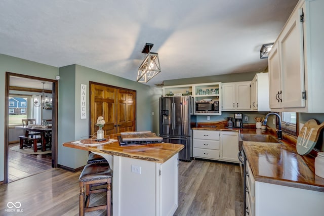 kitchen featuring a sink, stainless steel appliances, butcher block counters, and white cabinetry