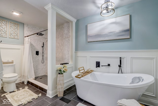 full bath featuring toilet, a freestanding tub, tiled shower, and a decorative wall