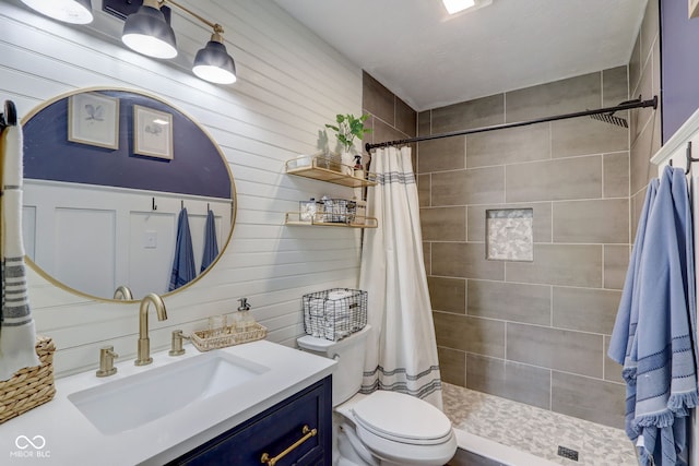 bathroom with toilet, a tile shower, and vanity