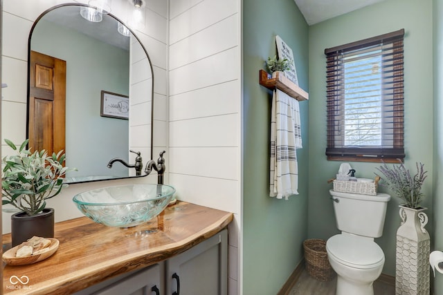bathroom with vanity, baseboards, wood finished floors, and toilet
