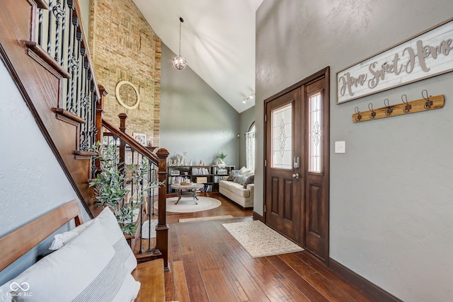 foyer with stairway, high vaulted ceiling, baseboards, and wood-type flooring