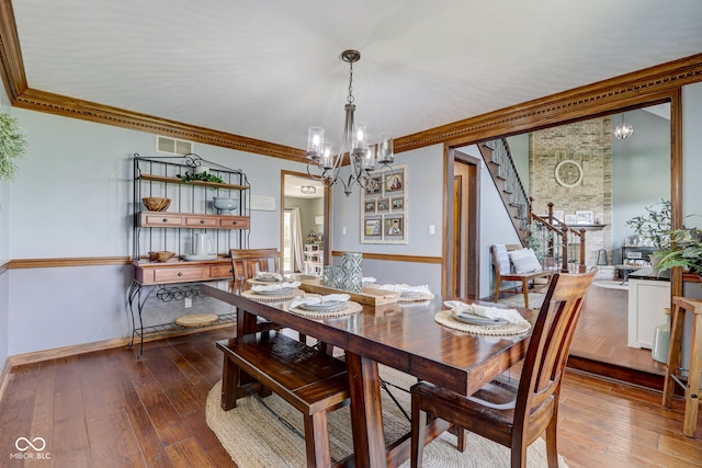 dining space with baseboards, visible vents, hardwood / wood-style floors, and a chandelier