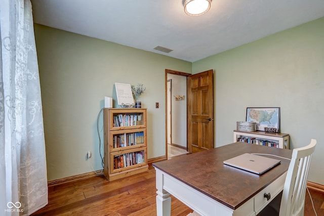 office featuring baseboards, hardwood / wood-style floors, and visible vents
