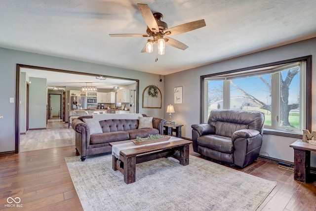 living room featuring wood-type flooring, a ceiling fan, and baseboards