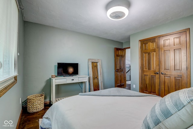 bedroom featuring baseboards, wood finished floors, and a closet