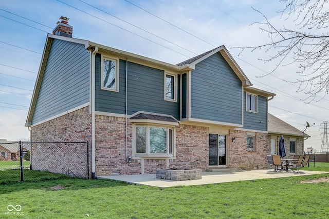 rear view of house featuring fence, a patio, a chimney, brick siding, and a lawn