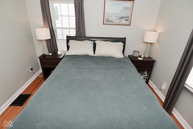 bedroom featuring baseboards, wood finished floors, and visible vents