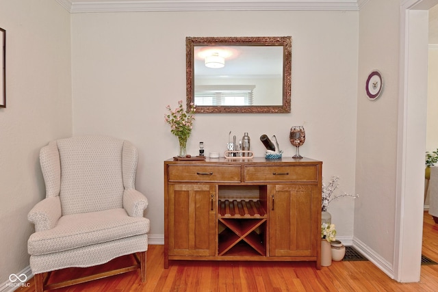 sitting room featuring baseboards, ornamental molding, and light wood finished floors